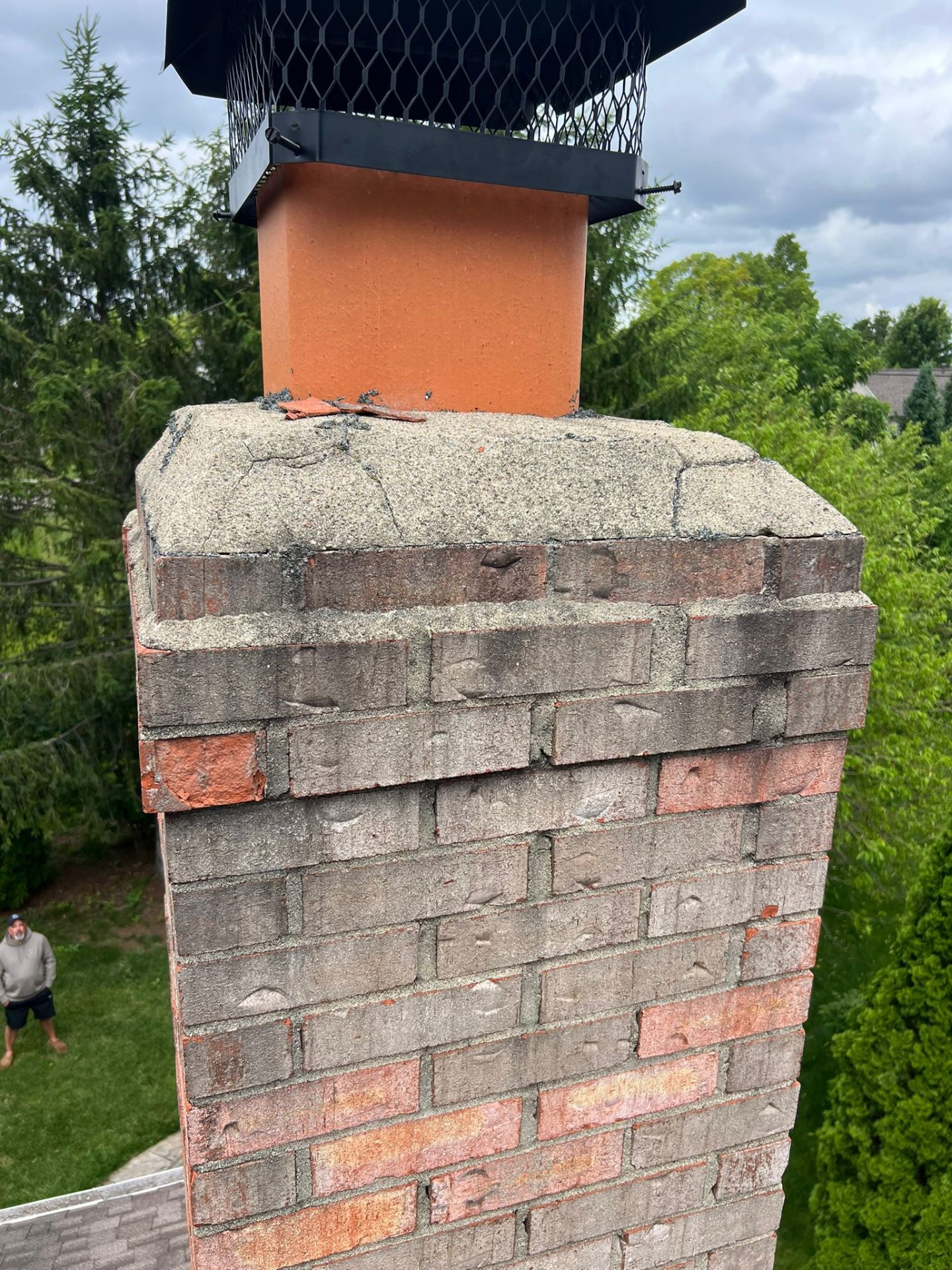 Cracked chimney crown with exposed terracotta flue before repair