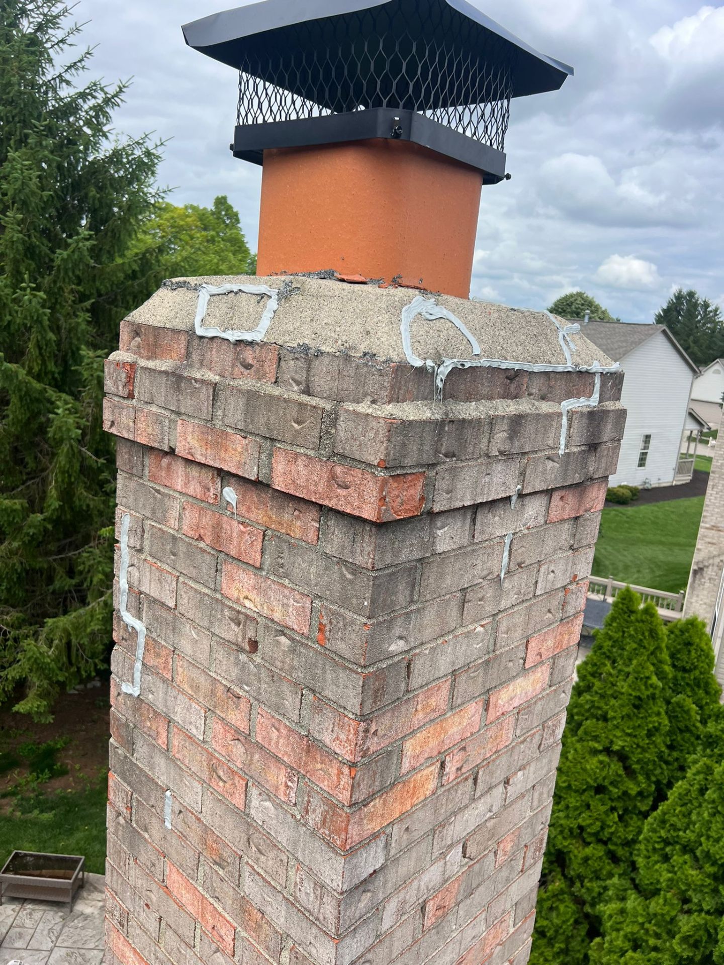 Crown sealed and new black mesh cap installed on a brick chimney